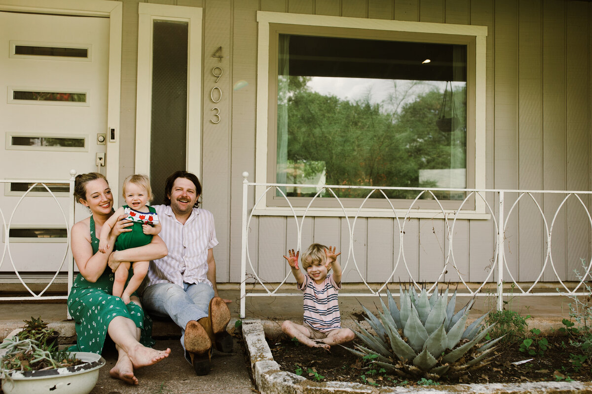 Family sitting on front porch of Austin home
