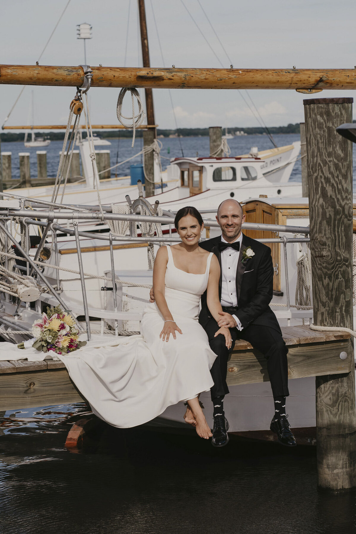Bride and groom sitting together on a dock