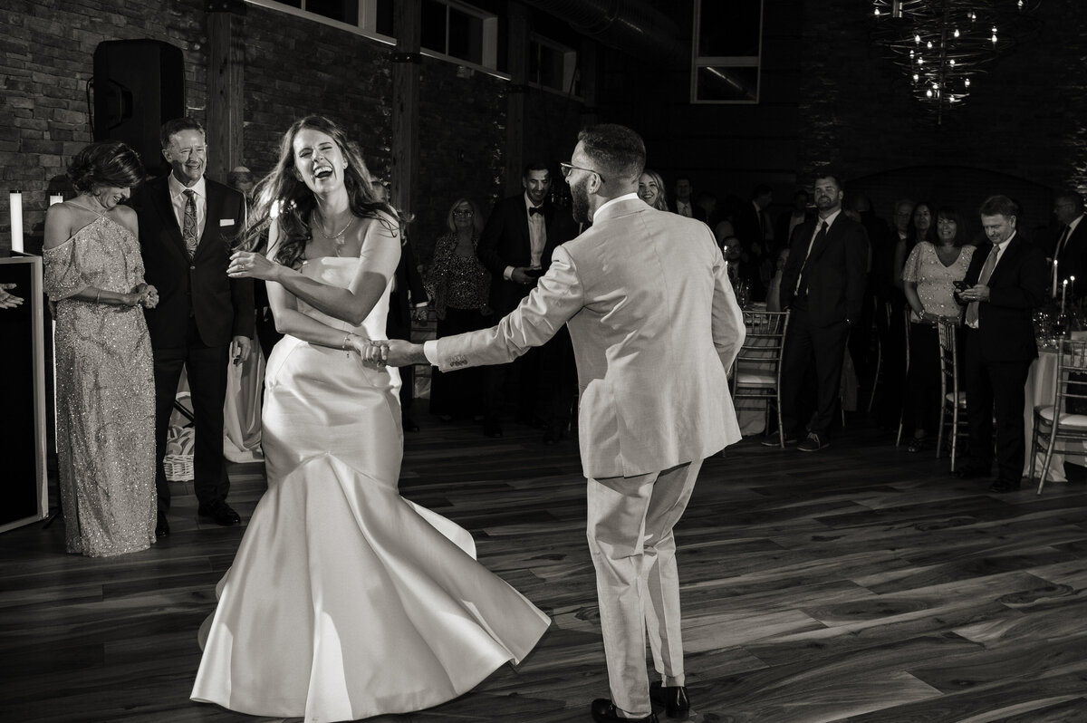 A wedding couple dancing and laughing at their reception 