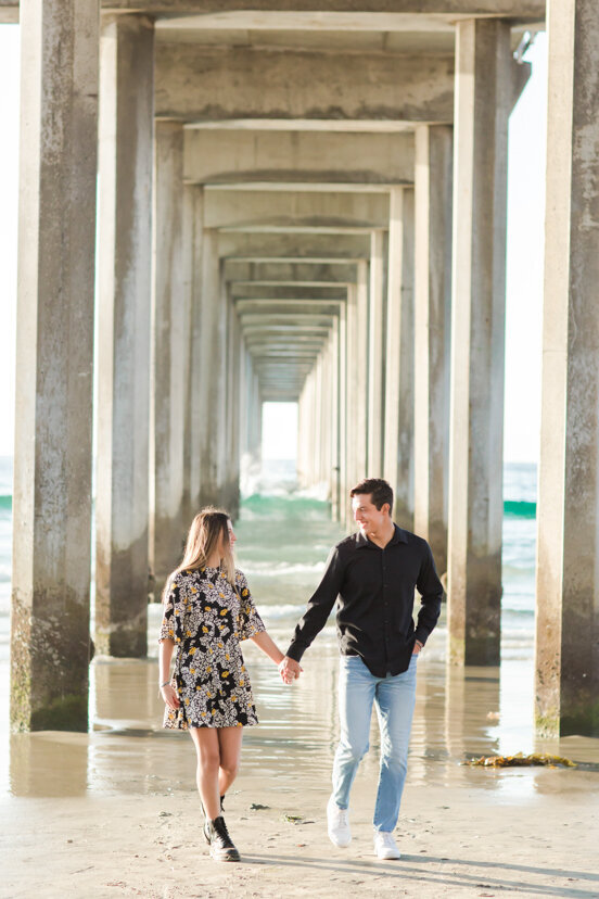 siblings-holding-hands-walking-under-Scripps-Pier-San-Diego