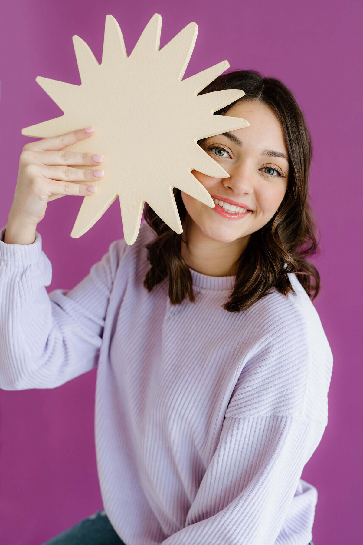 candid studio portrait of senior girl in light purple sweater with purple background in Shreveport, LA photography studio