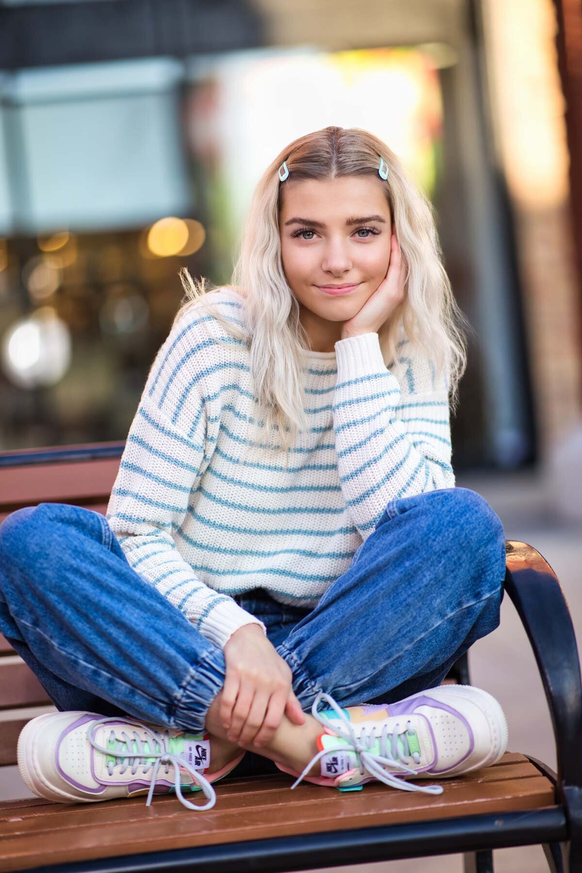 Cute senior girl wearing Nike shoes posing on bench for senior portraits in Utah.