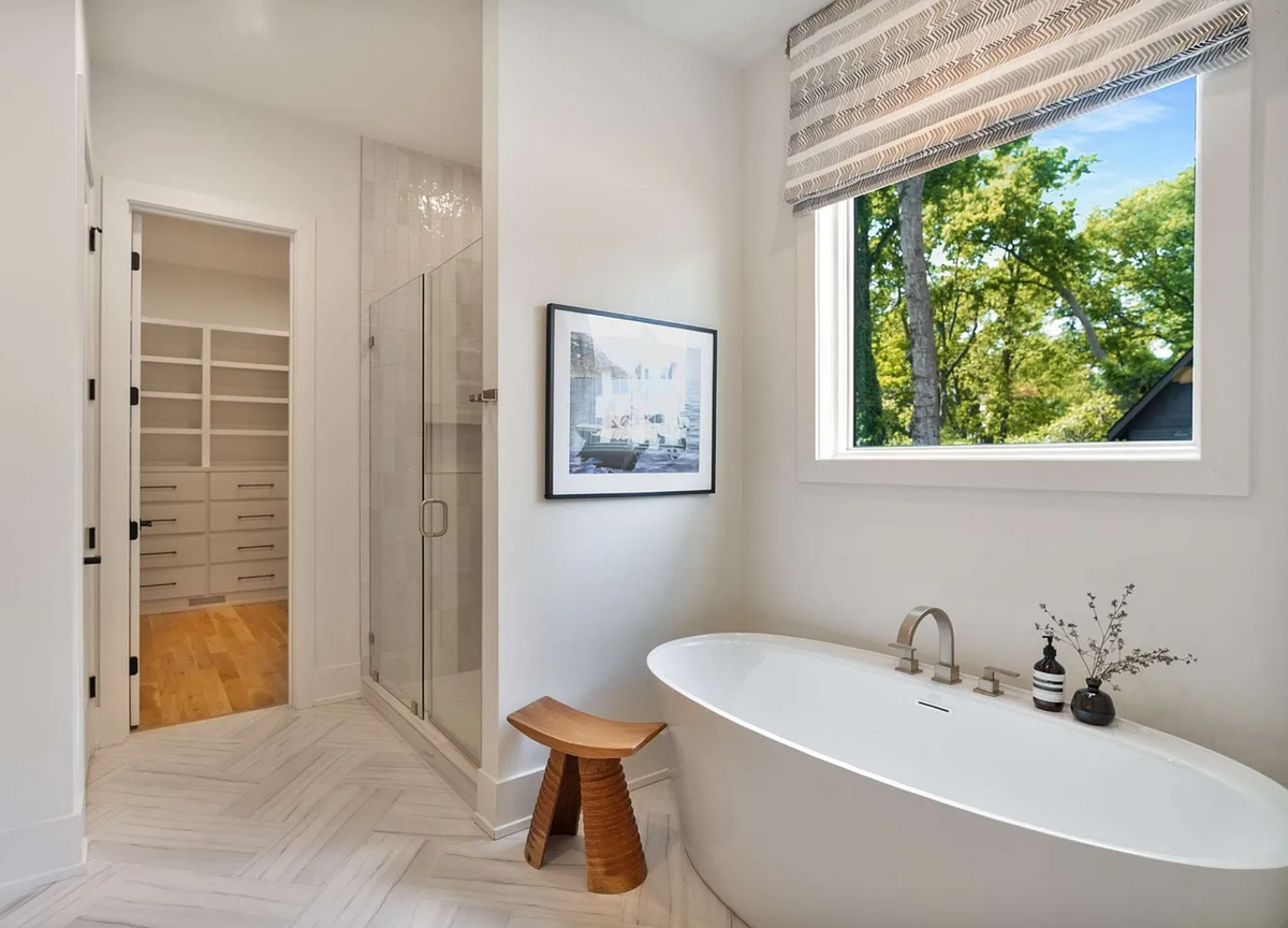 Tranquil bathroom with soaking tub, glass walk-in shower, herringbone tile flooring, and direct access to a custom walk-in closet