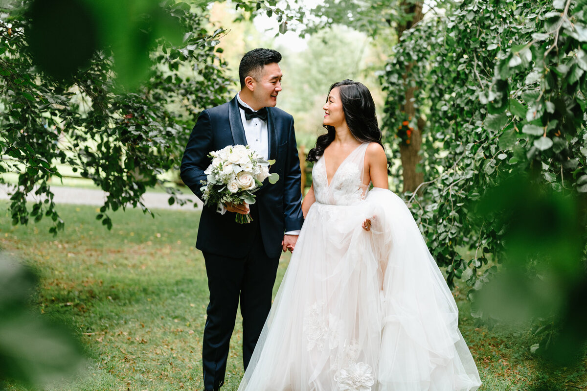 Stunning bright and groom wander tree lined paths on their wedding day