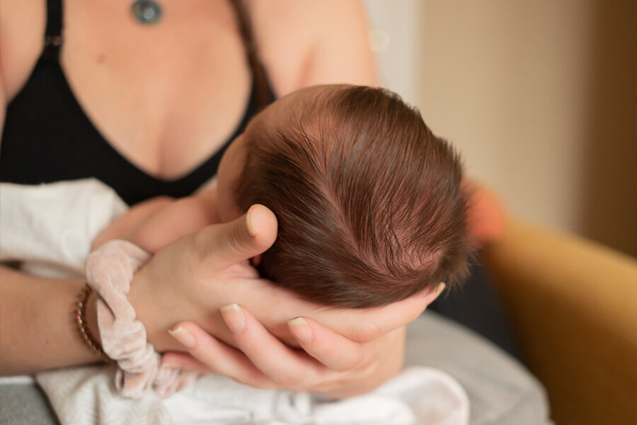Back of a newborn baby's head being held in mom's hands.