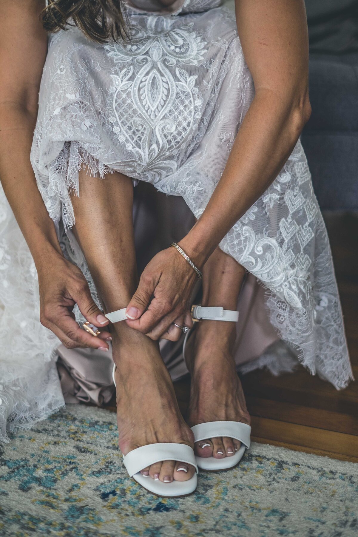 a bride putting on her white wedding shoes