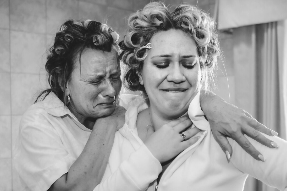 The bride and her mother cry with  curlers in their hair