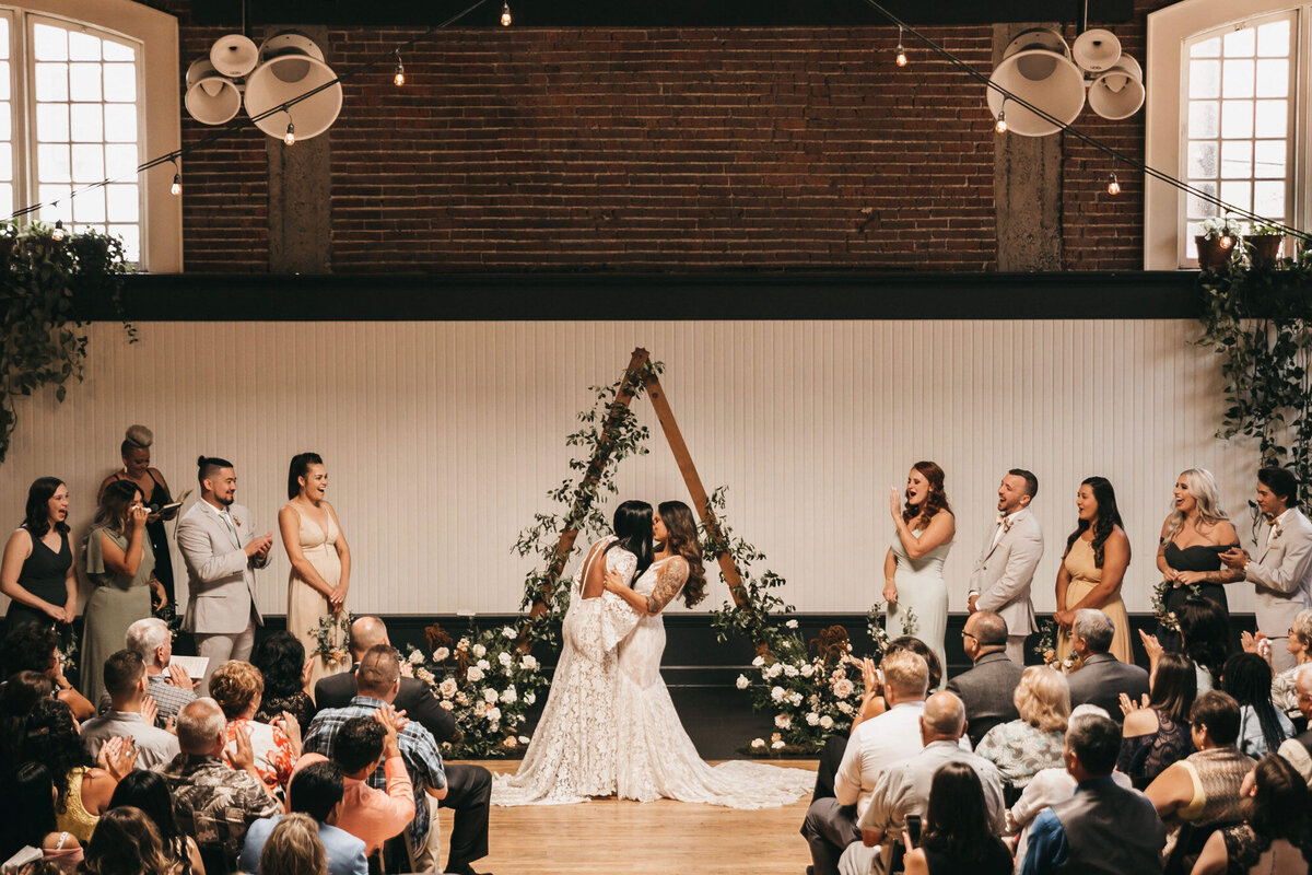 Married couple kissing each other at their wedding ceremony and guests cheering them up