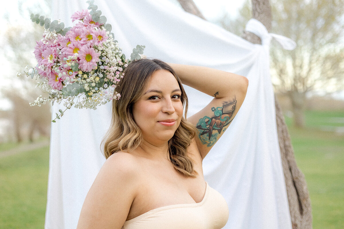 A woman poses with flowers behind her head