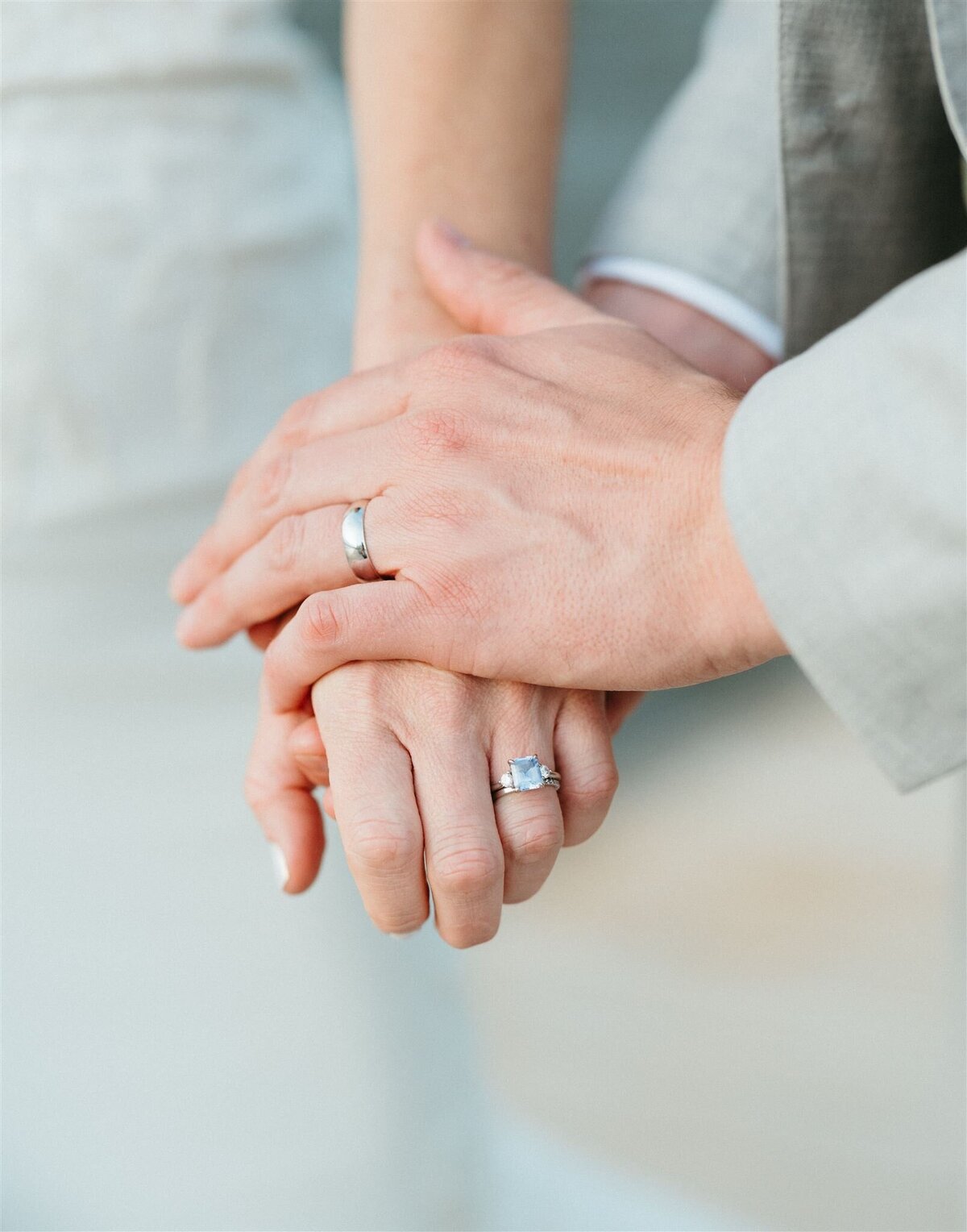 a couple holding hands showcasing their wedding rings