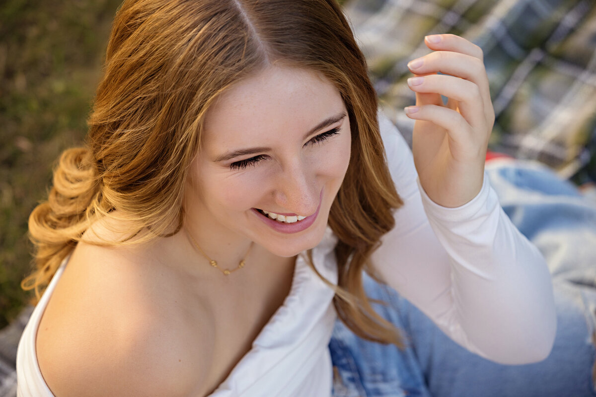 Giggling close-up from above of a high school senior in casual jeans and white top outfit