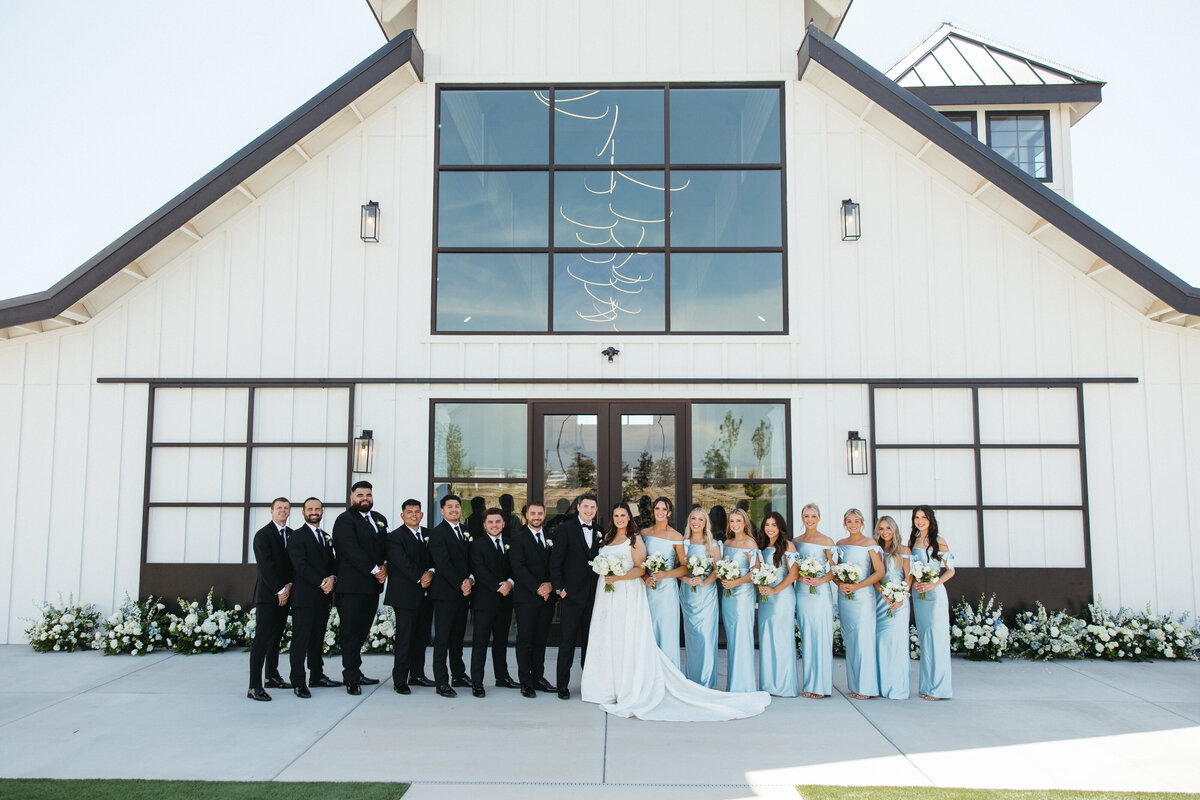 bride and groom posing with bridal party in front of venue