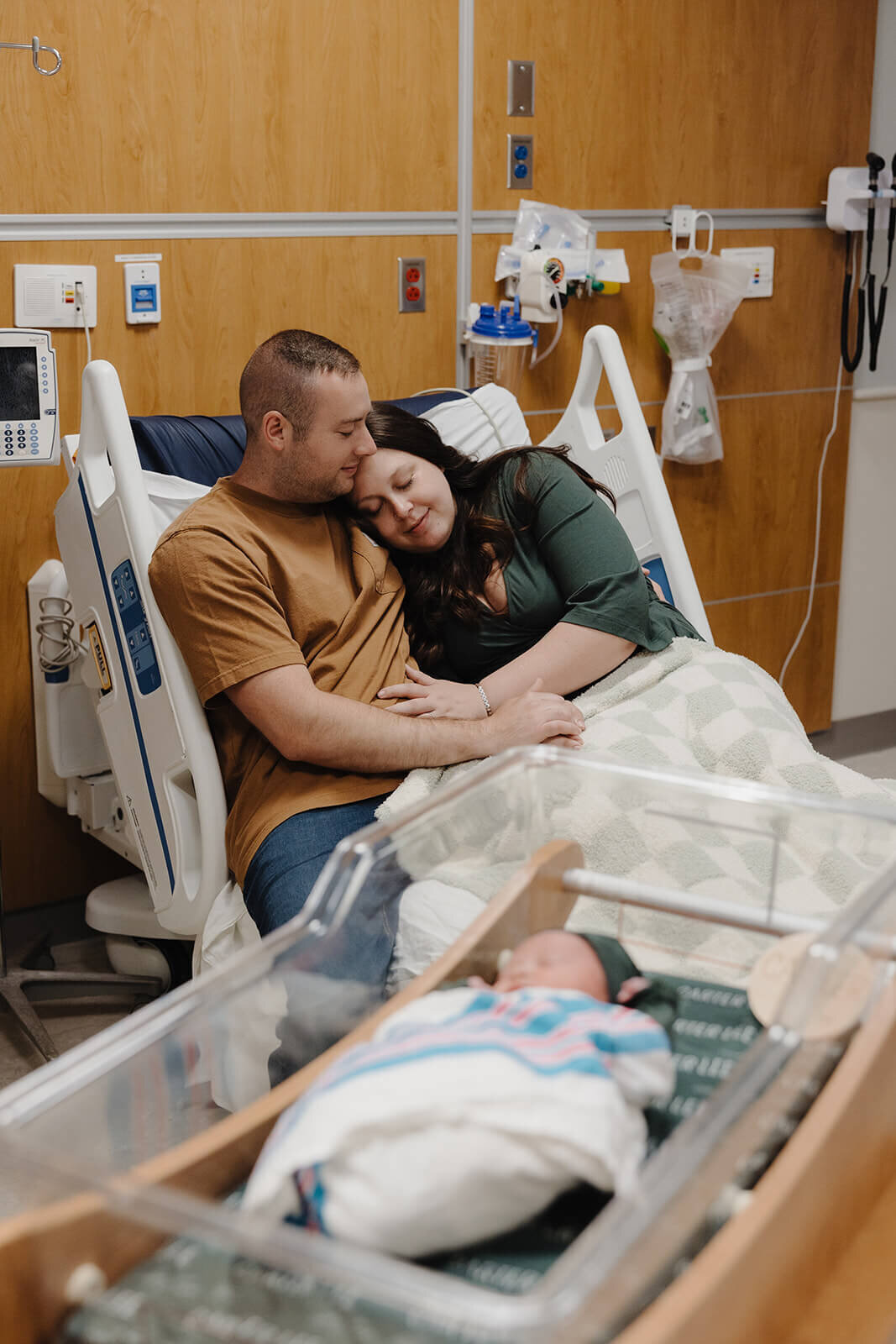newborn baby in crib with mom and dad lying in bed  at newborn photoshoot at Finger Lakes, New Yok