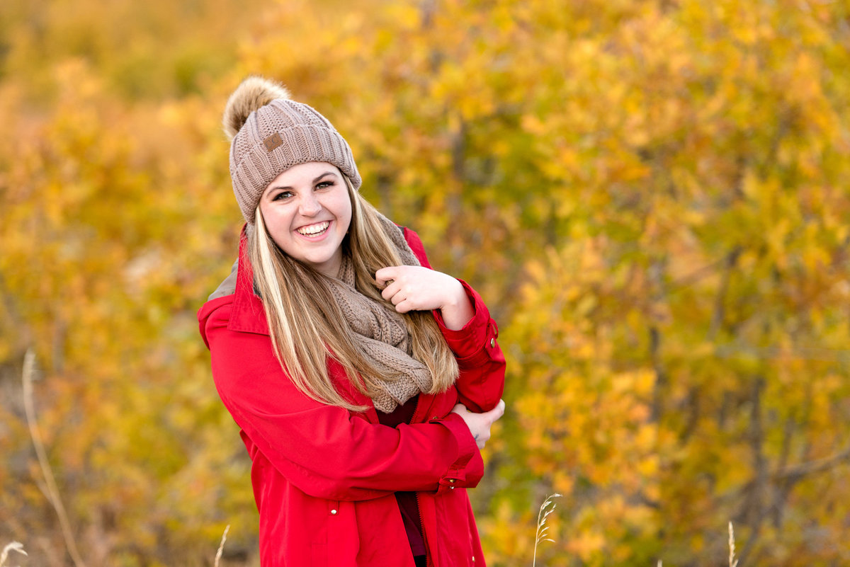senior girl smiles at the camera during the fall at snowbasin