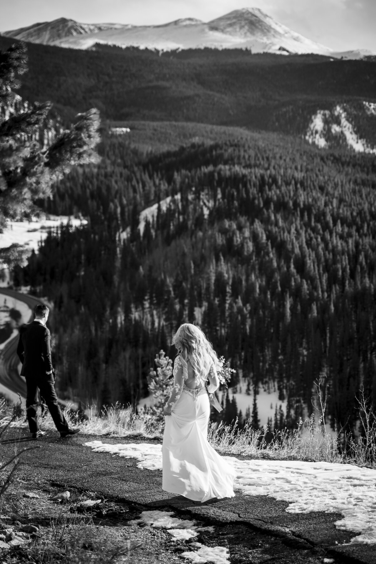 A bride approaches her groom for their first look on a snowy mountainside.