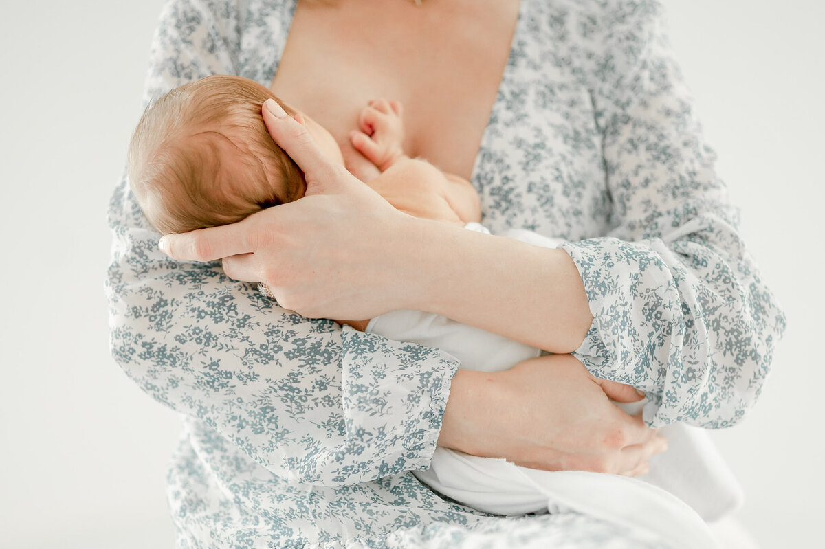 a mother nurses her newborn baby in Kristie Lloyd's nashville newborn photography studio