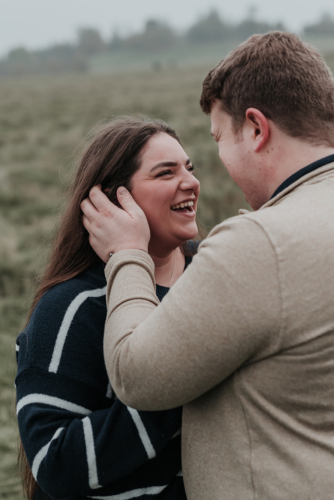 Man softly touches his fiance's cheek as she smiles up at him
