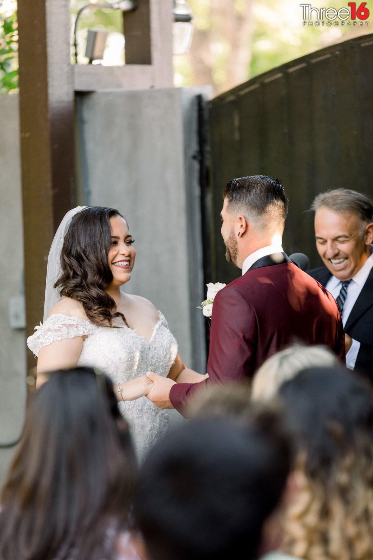Bride, Groom and Officiant all share in a laugh together during the ceremony