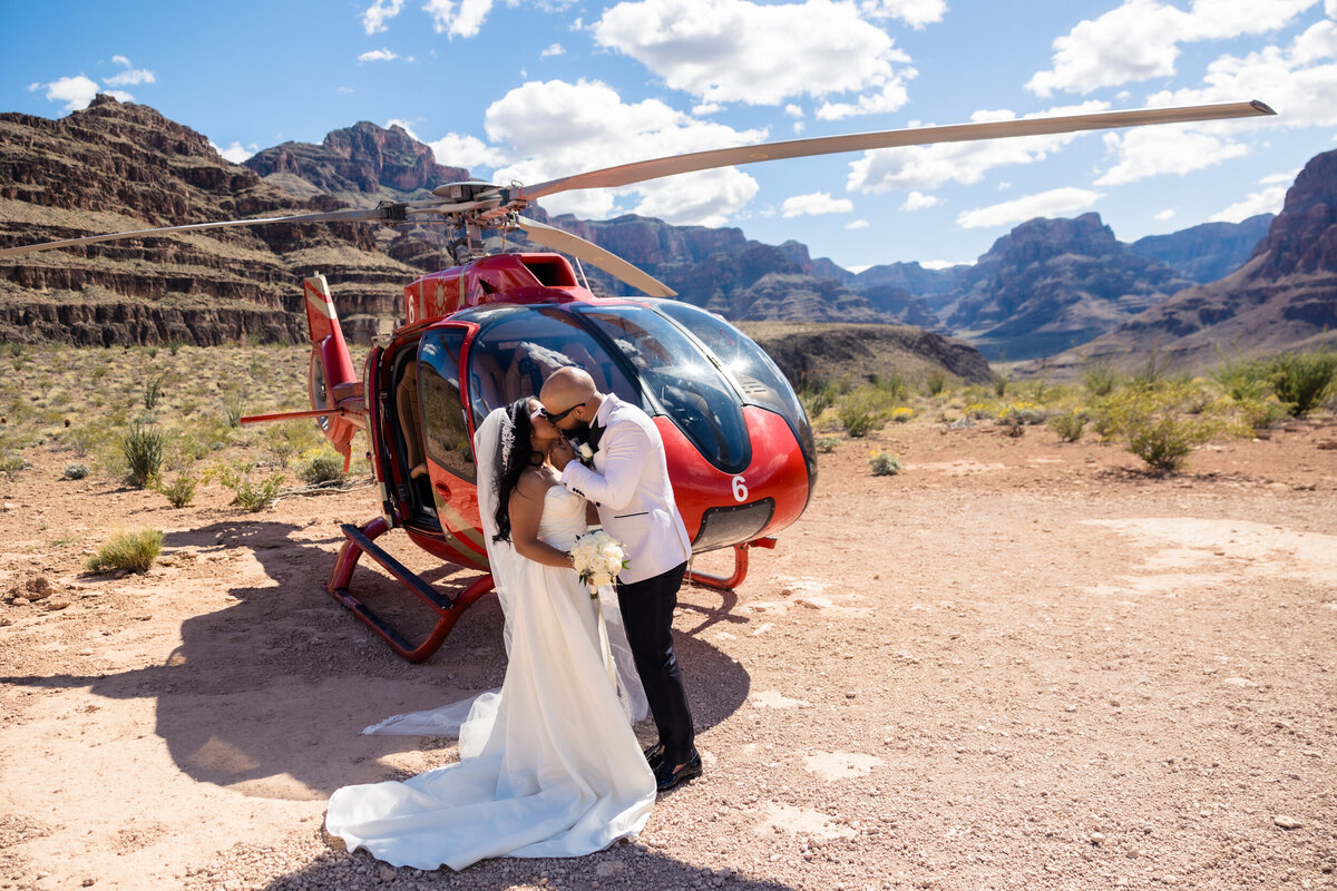 Bride and groom kissing in front of helicopter at the grand canyon.