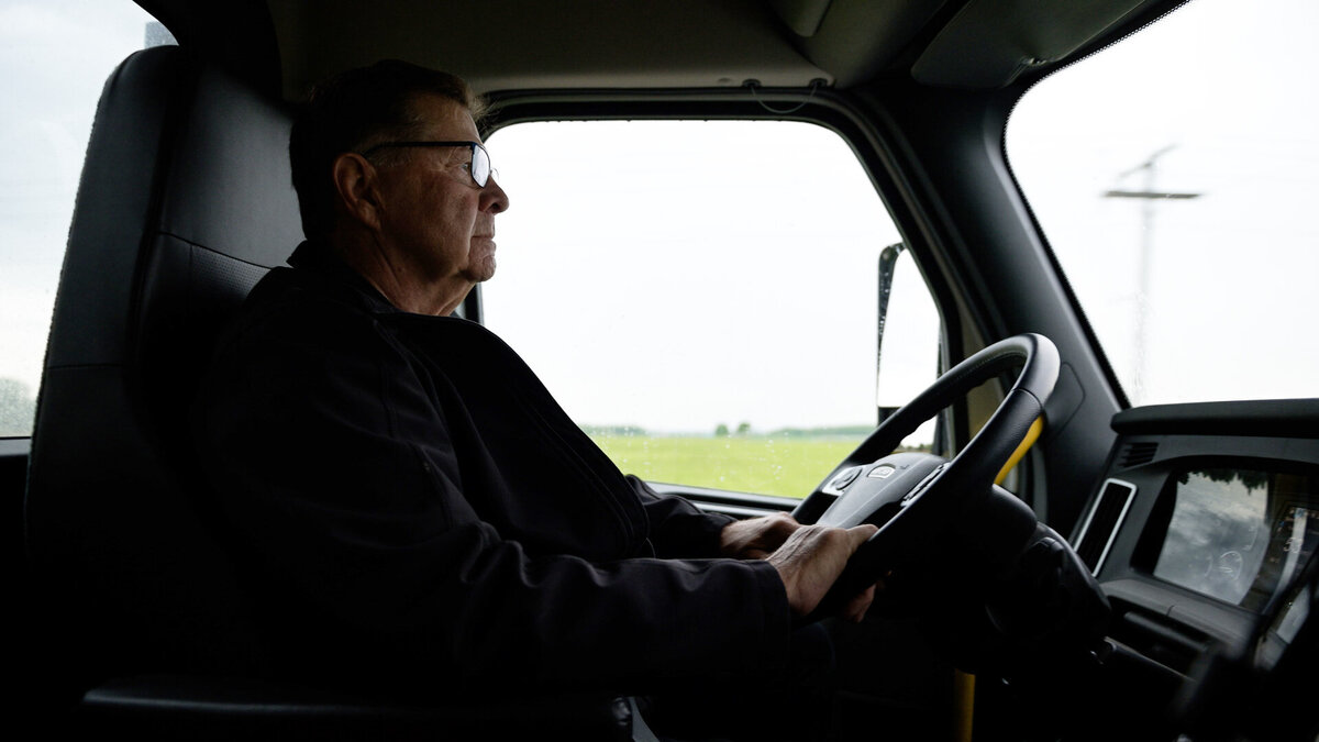 A portrait of John Robinson, a veteran truck driver for Gray Ridge Egg Farms in Ontario, captured in his truck during a workday. The image highlights his dedication and decades of experience on the road, as featured in a documentary project by Brandon Marsh Photo & Video Productions.