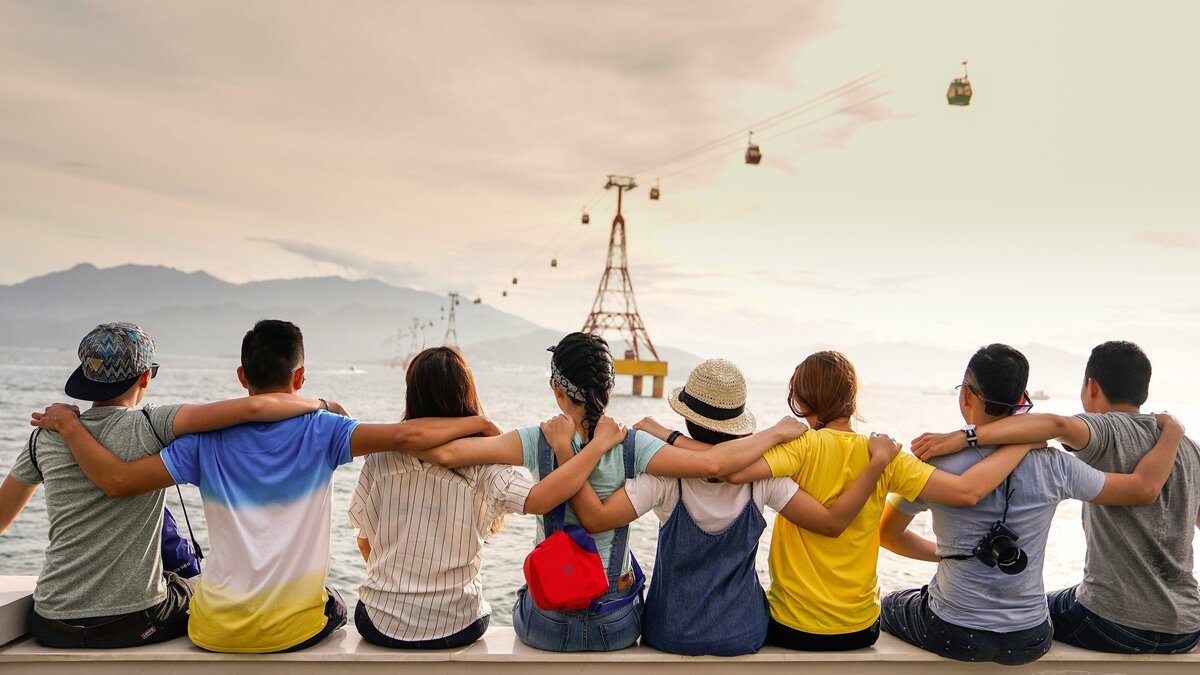 Group of people on vacation sitting on a ledge looking out.