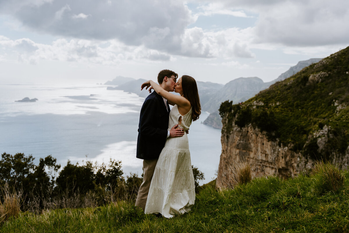 Couple kissing on a cliff edge.