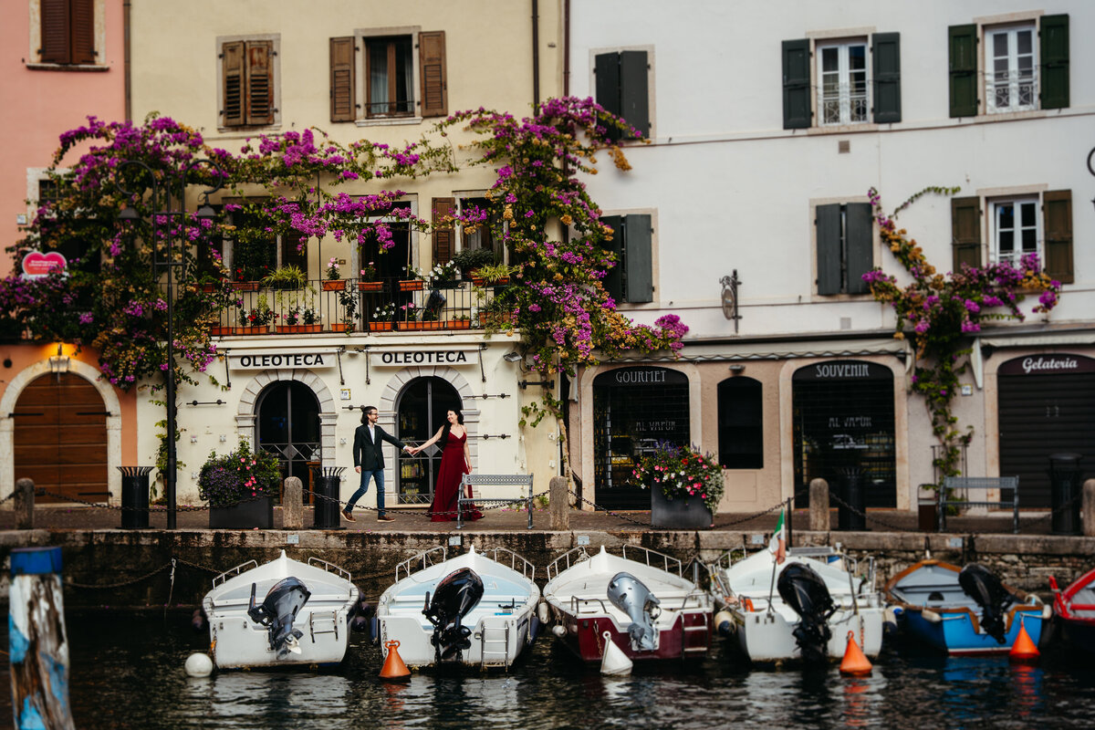 Lake Garda honeymoon session couple walking by the water with city lights in the background