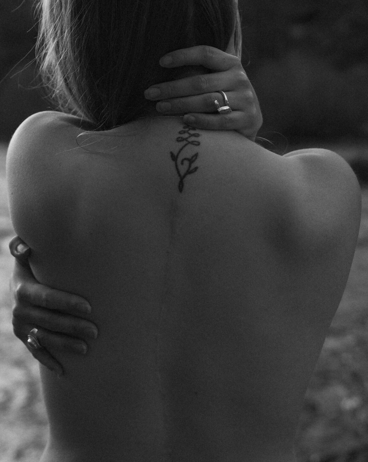 woman with tattoos and silver rings hugs herself at the river in Bend, Oregon