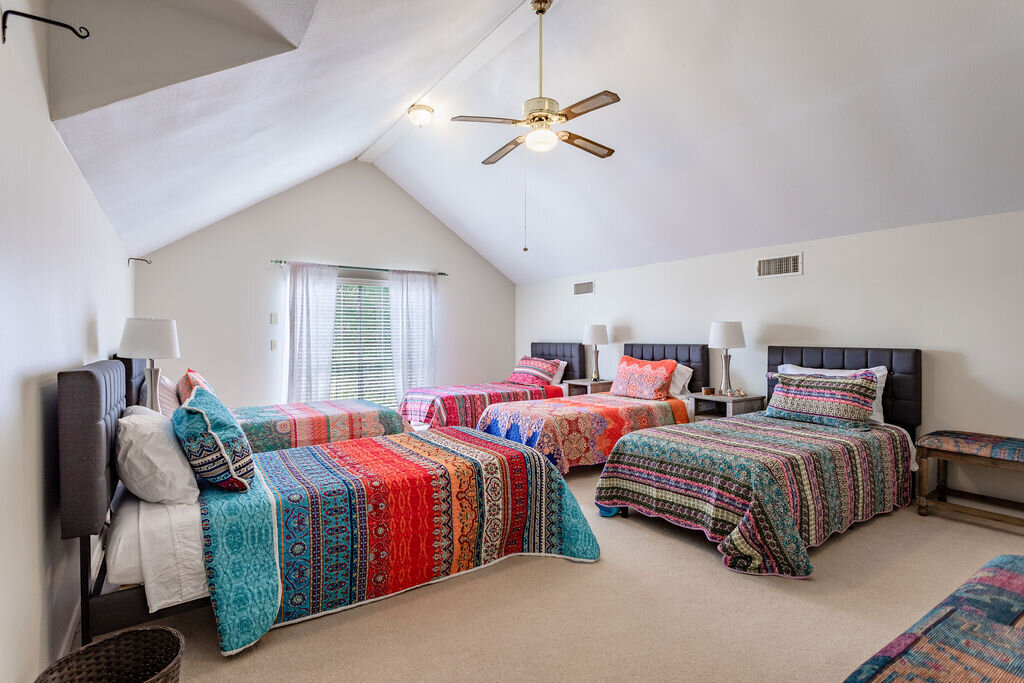 Bedroom with five twin size beds in this 5-bedroom, 4-bathroom vacation rental house for 16+ guests with pool, free wifi, guesthouse and game room just 20 minutes away from downtown Waco, TX.