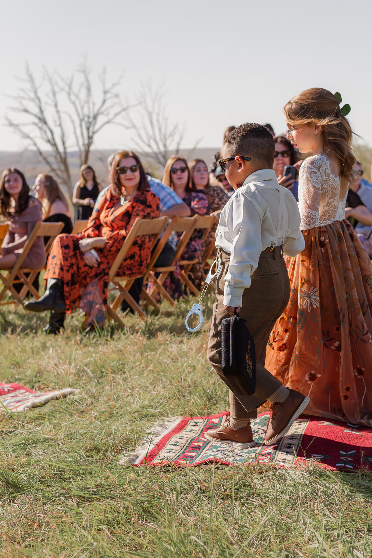 Ring bearer and flower girl walking down the aisle on layered boho rugs during a fall wedding ceremony at Jerry Coopers Ranch in Pennsylvania.