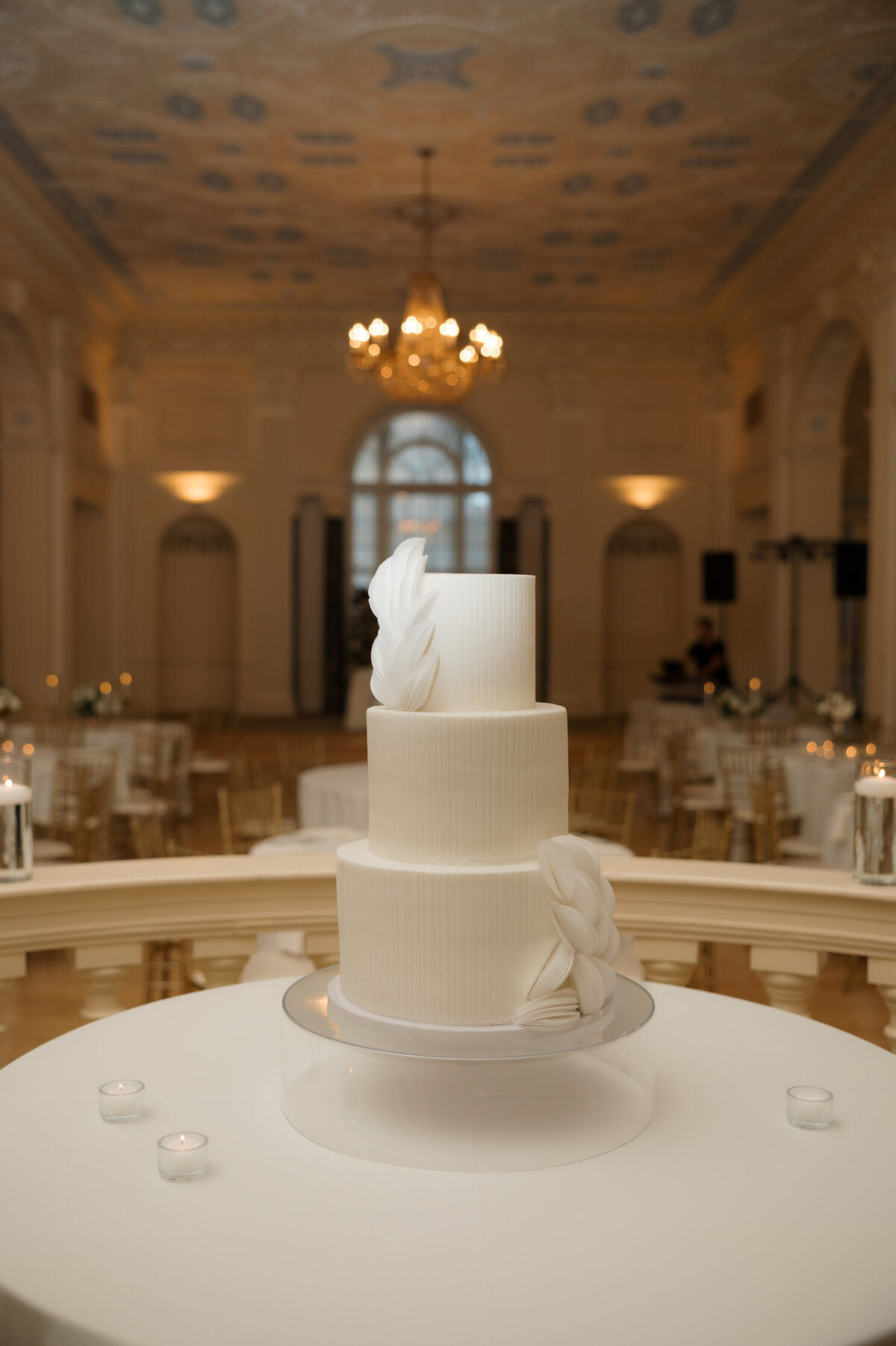 Close-up of a white wedding cake surrounded by candles on a round table.