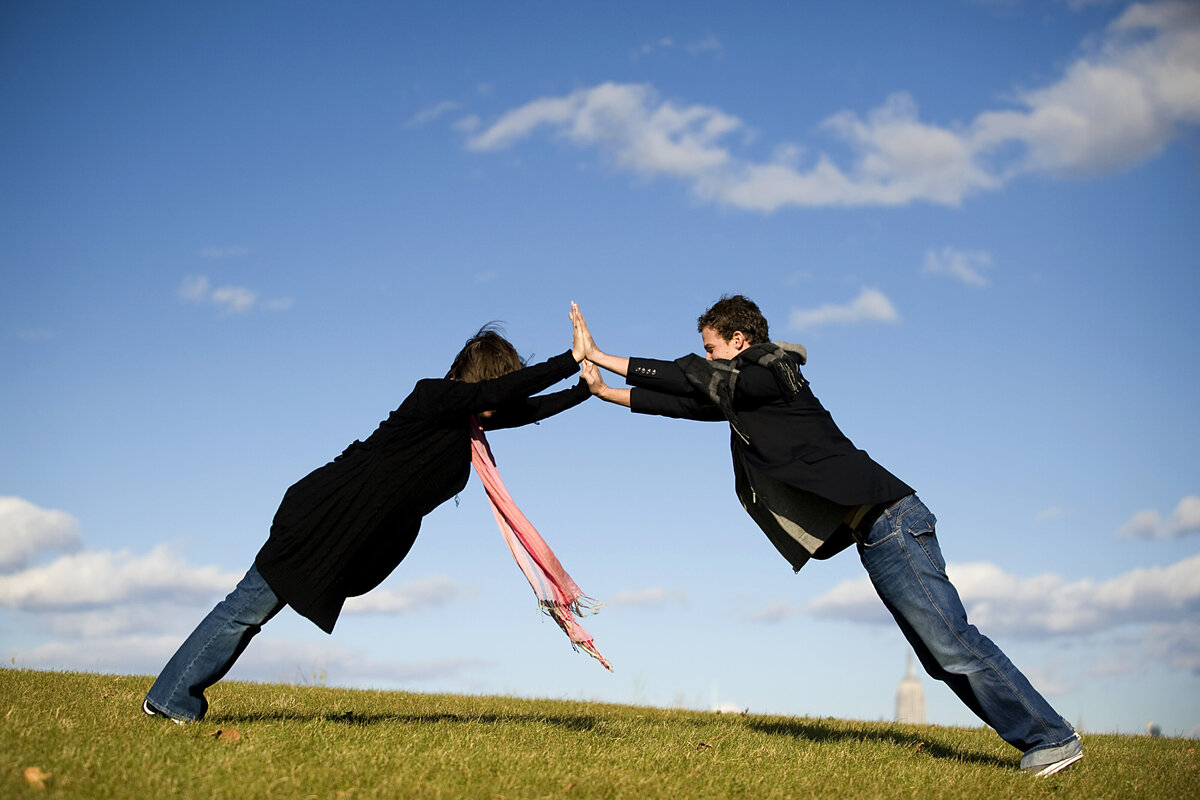 A couple leaning forward with their palms together creating an arch