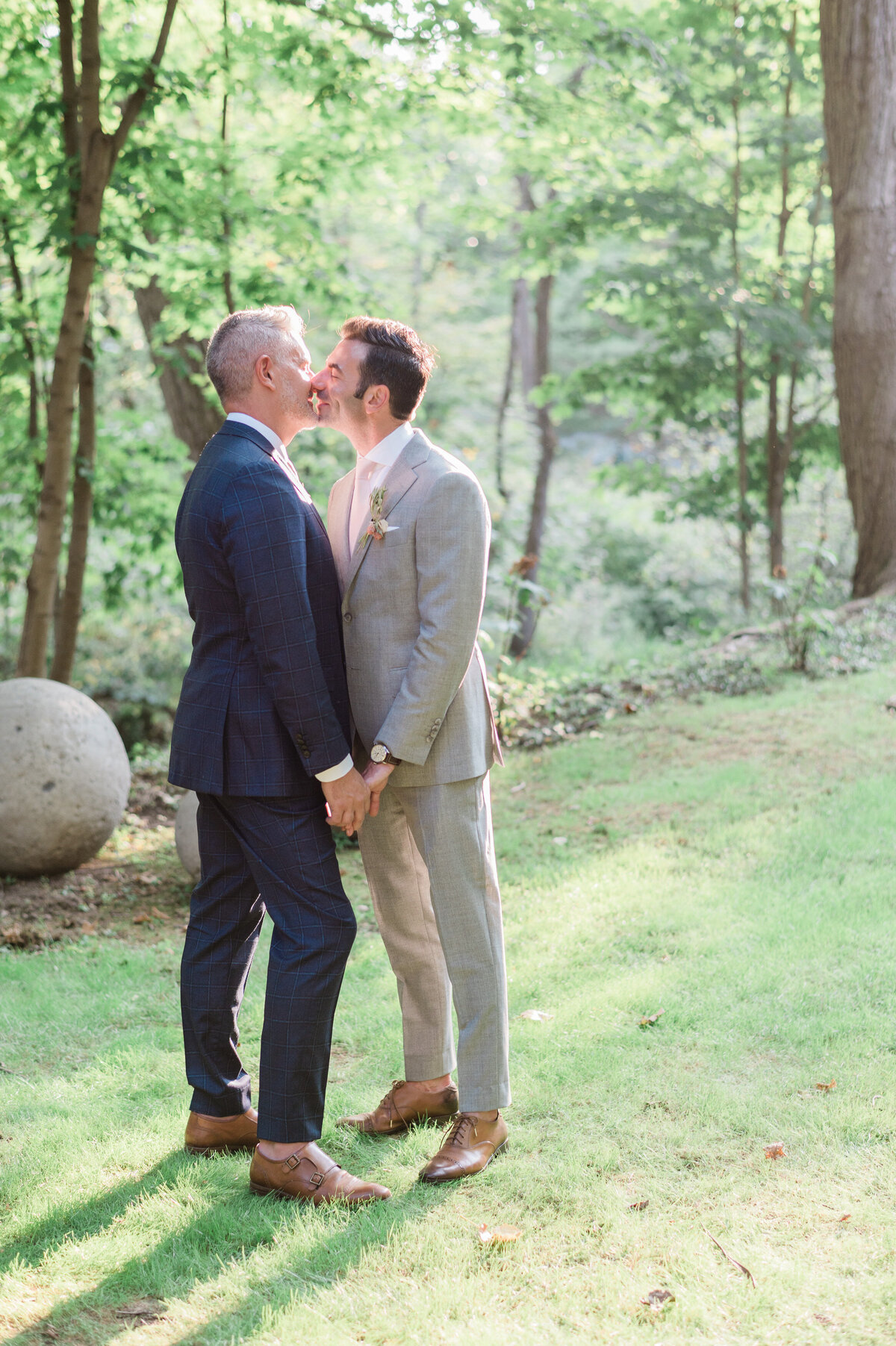 Husbands kiss in the grass of a Hudson Valley estate 