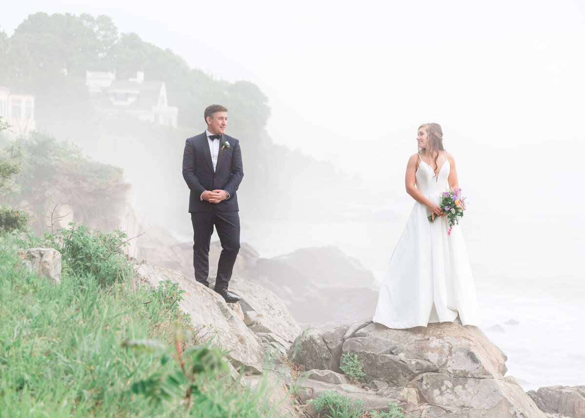 adventurous bride and groom standing on rocks at York Harbor beach for york Inn Wedding  (5)