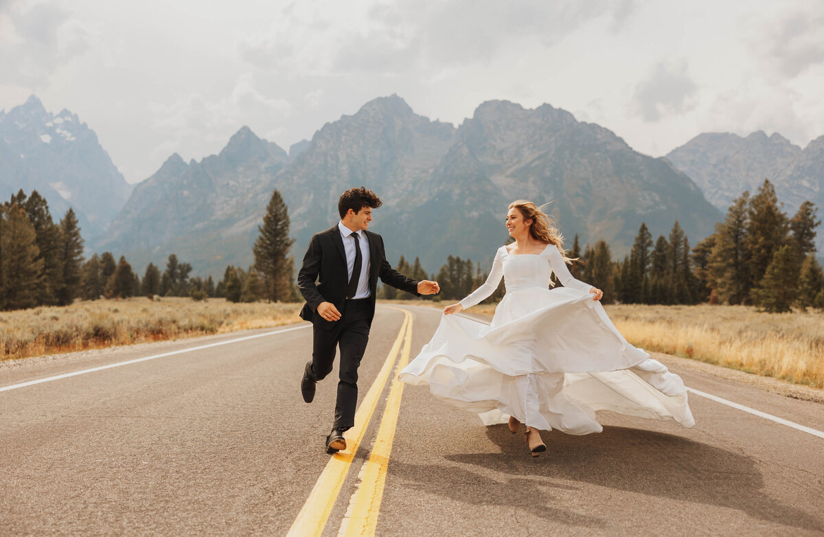 brid eand groom holding hands in road