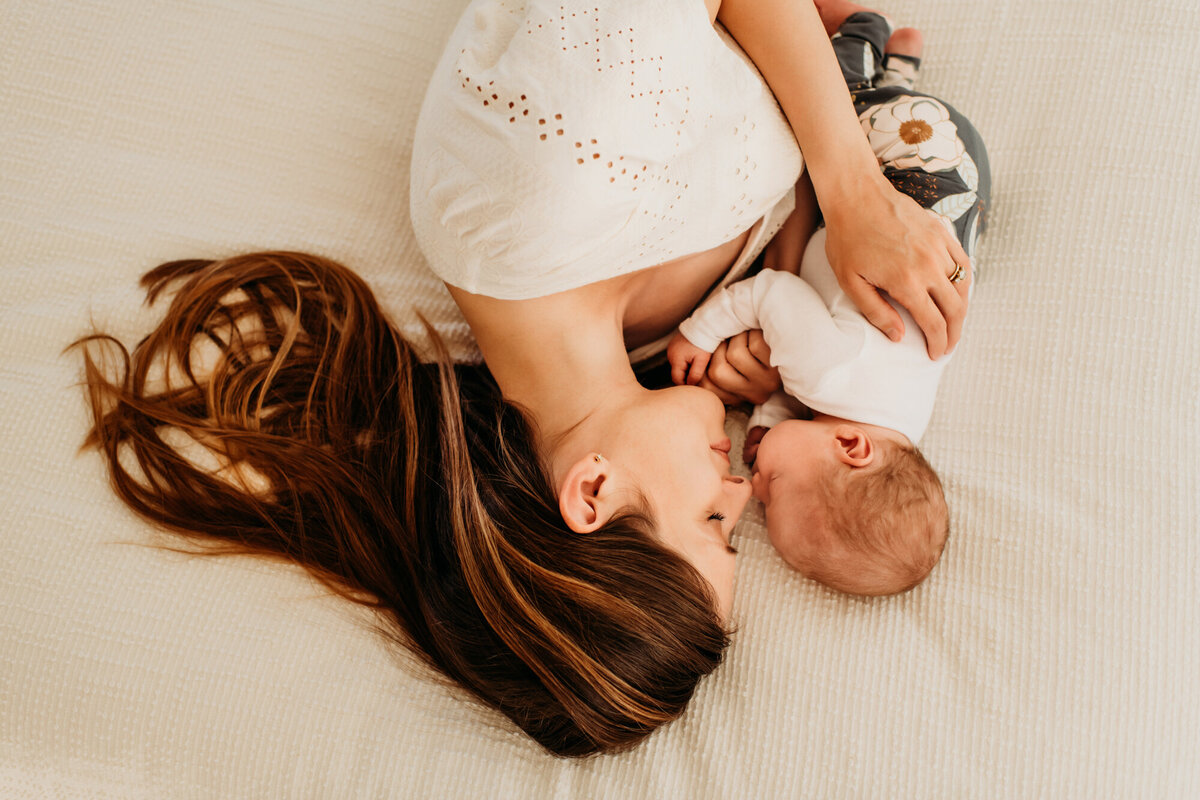 Newborn Photographer, Mom laying on the bed with her nose to nose with her baby girl.