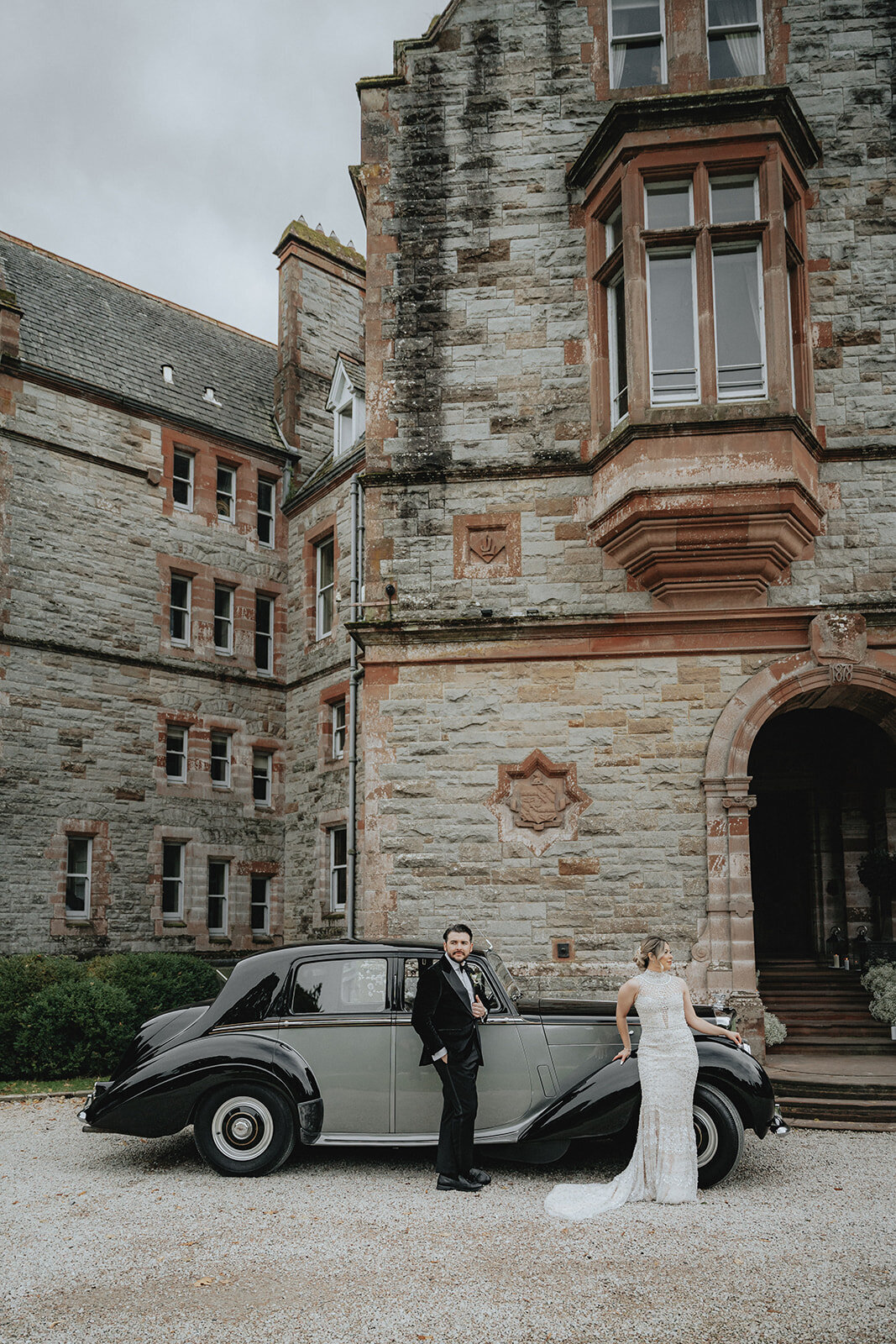 Bride and groom leaning against old car in Ireland