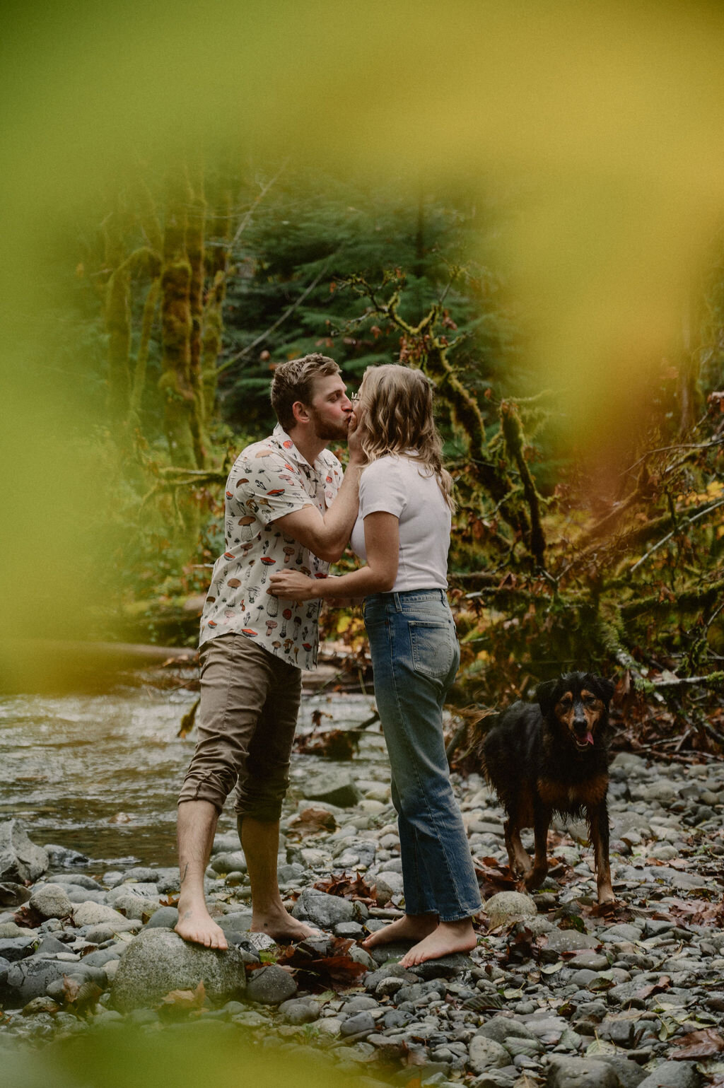 Couple kissing by the river with dog in bare feet