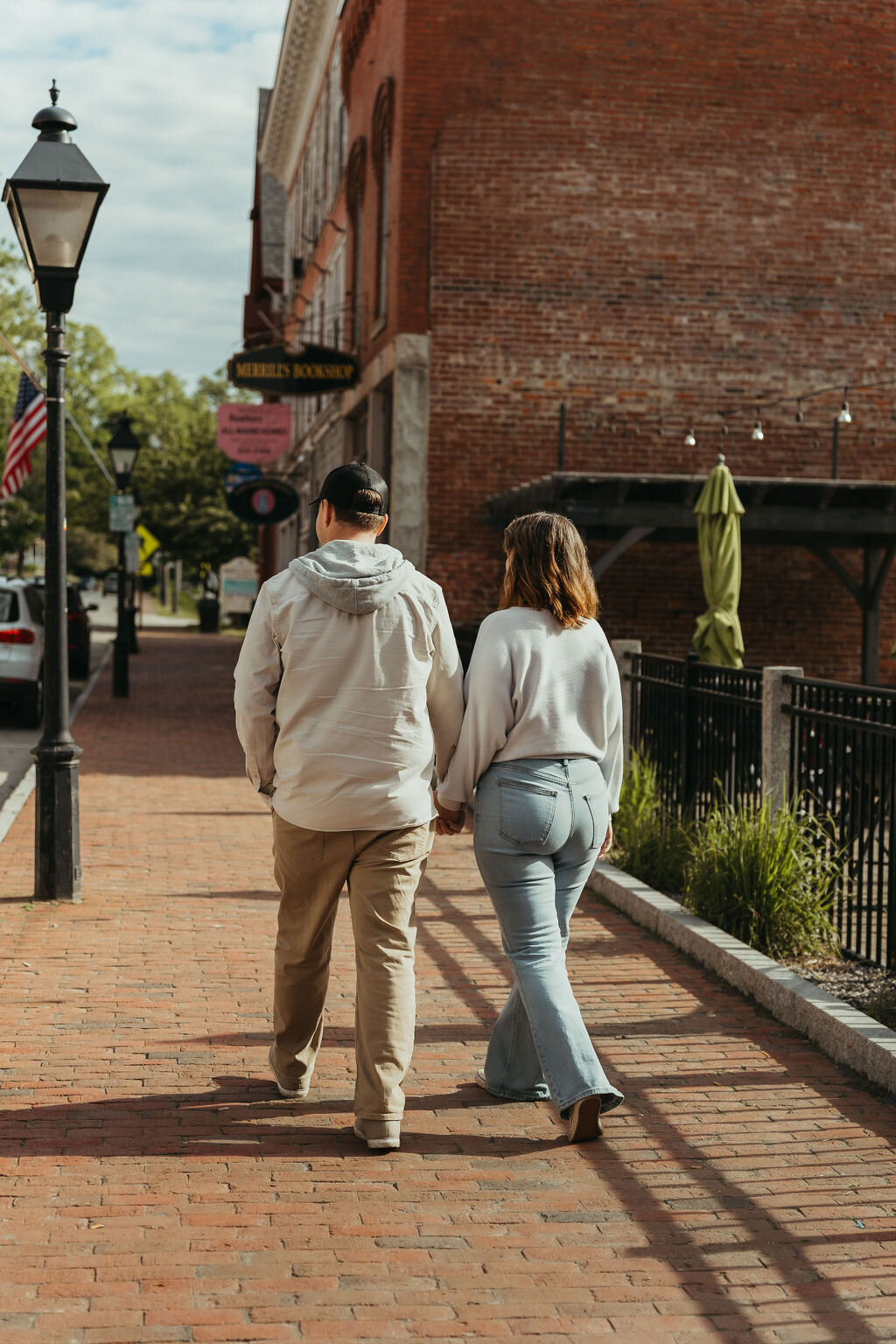 Photo of couple holding hands walking together downtown Central Maine