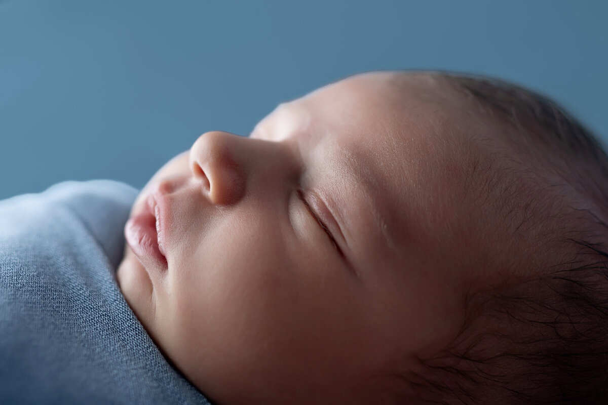 Details of a baby sleeping in a blue swaddle