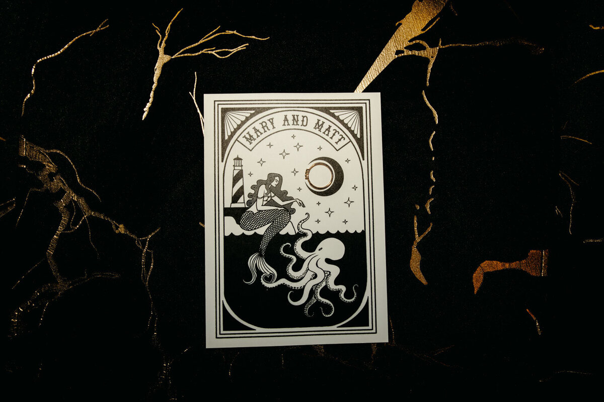 Black and white wedding invitation featuring underwater theme with an octopus and a woman swimming