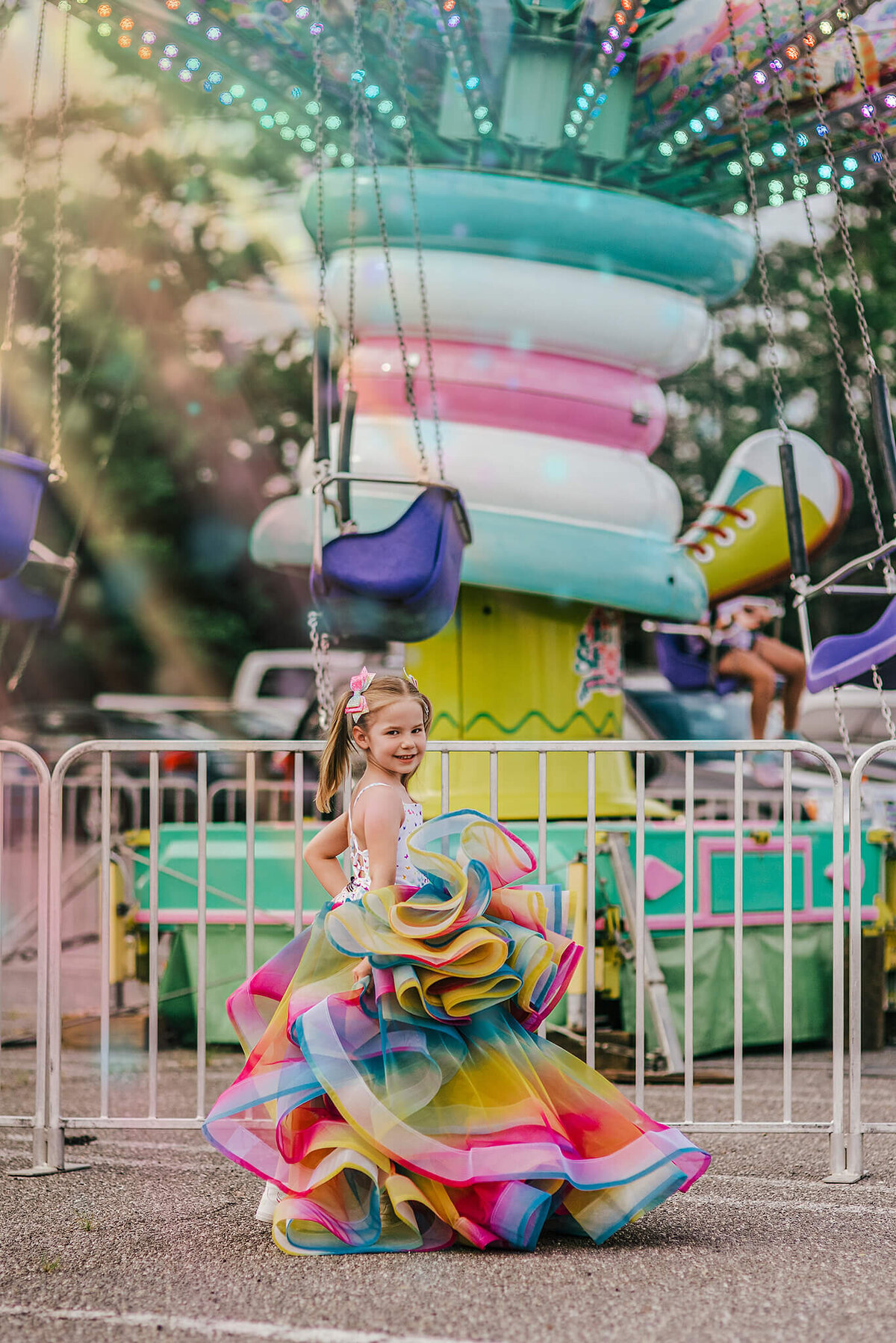 Girl in pigtails wearing a rainbow dress and spinning in front of a carnival ride near Annapolis Maryland