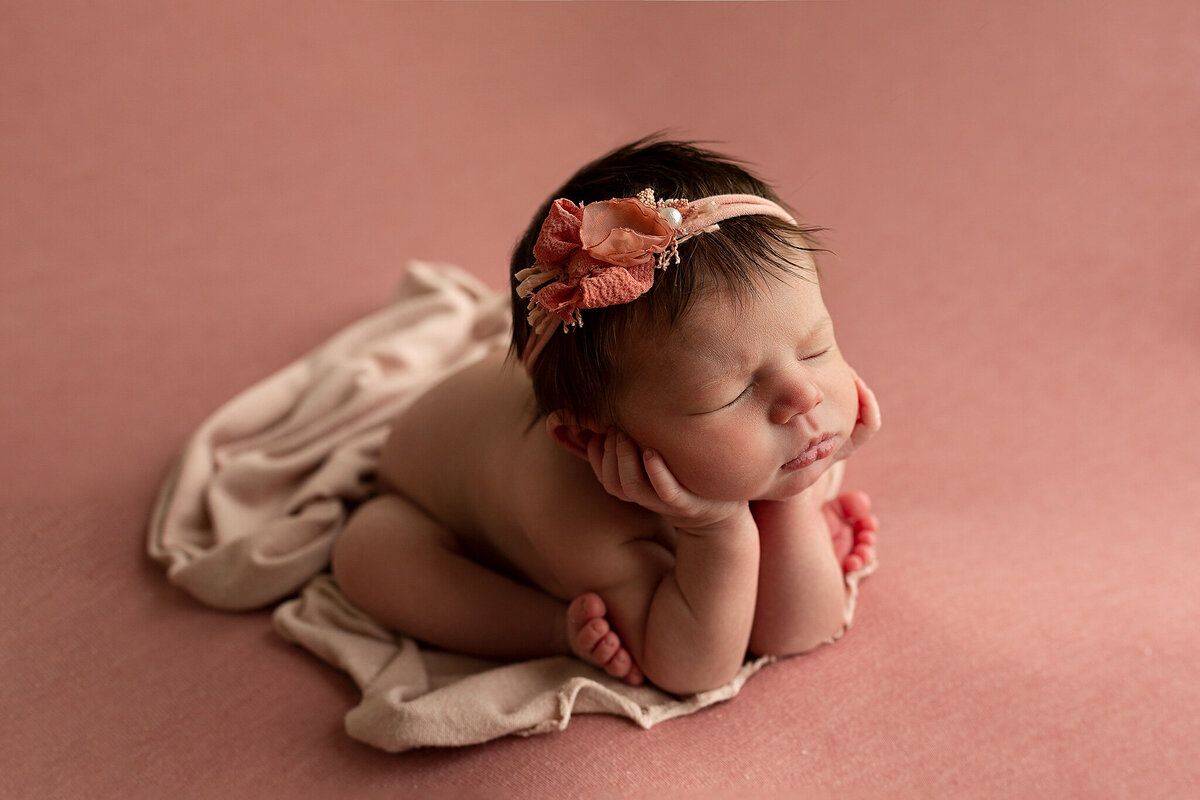 columbus-ohio-newborn-baby-girl-in-froggy-pose-head-in-hands-on-dark-pink-blanket