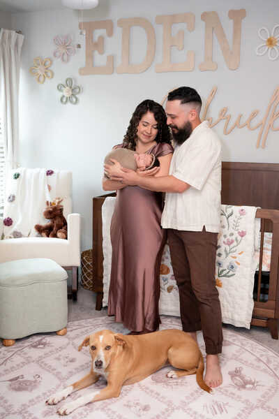 Parents smiling together while holding their newborn during Houston family portraits.