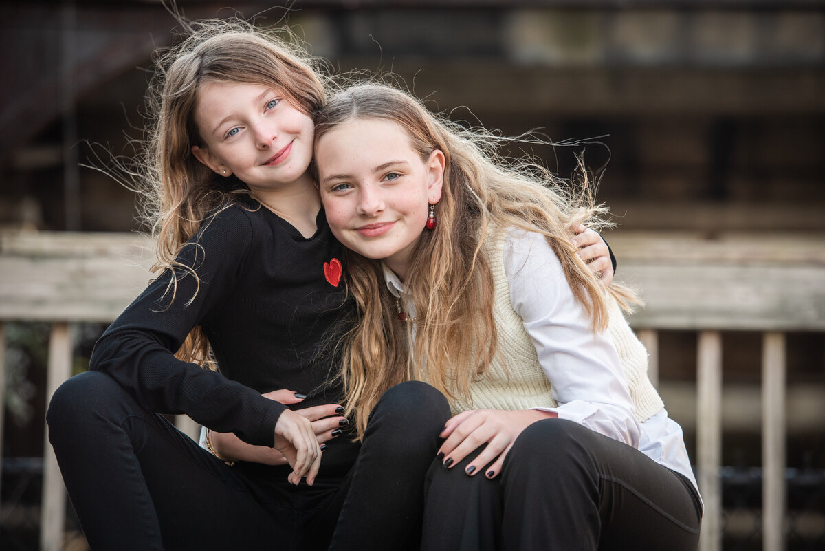Two sisters smiling with their arms around each other