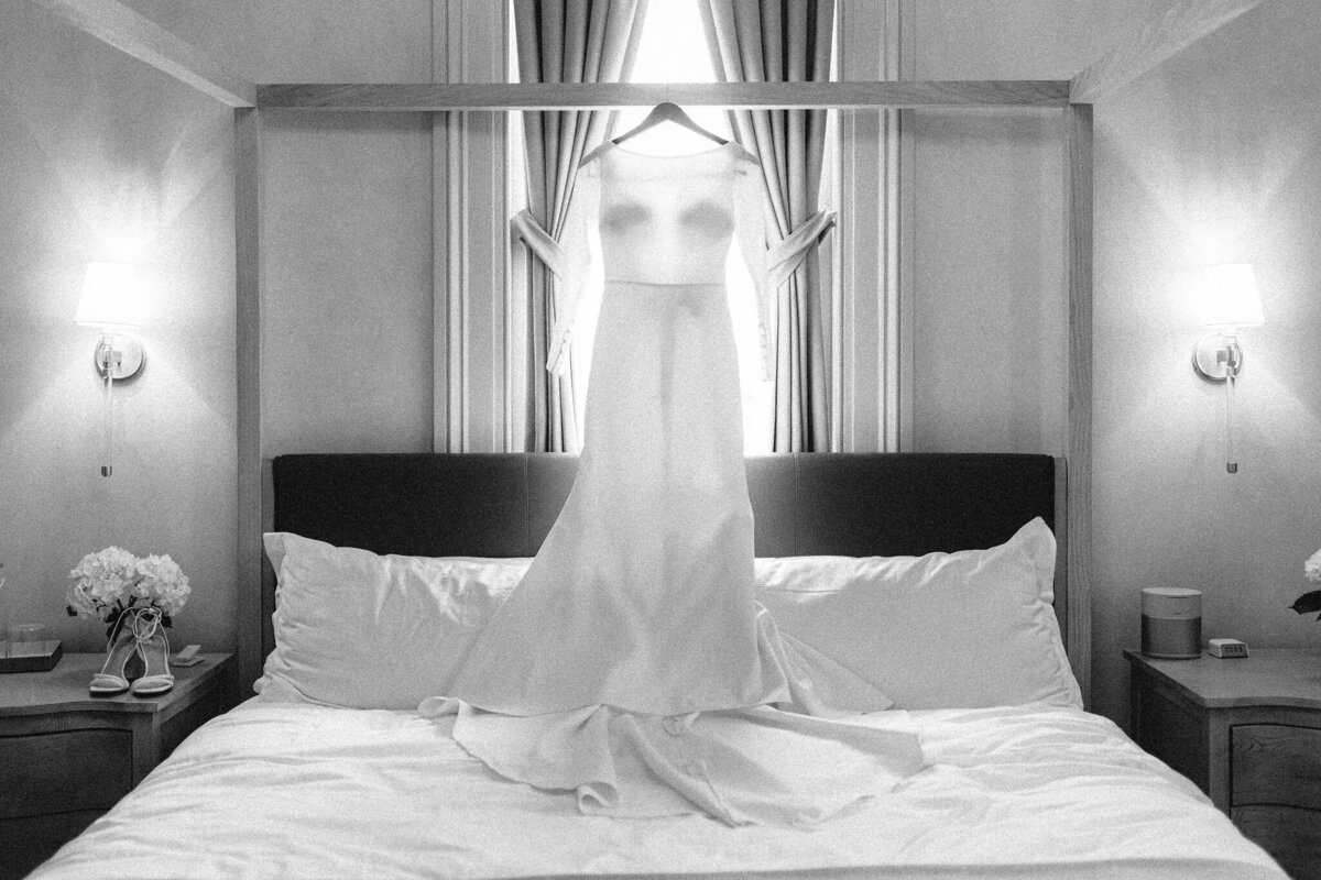 Luxury black and white photo of a long sleeve wedding dress on a canopy bed at the Heights House in Raleigh NC