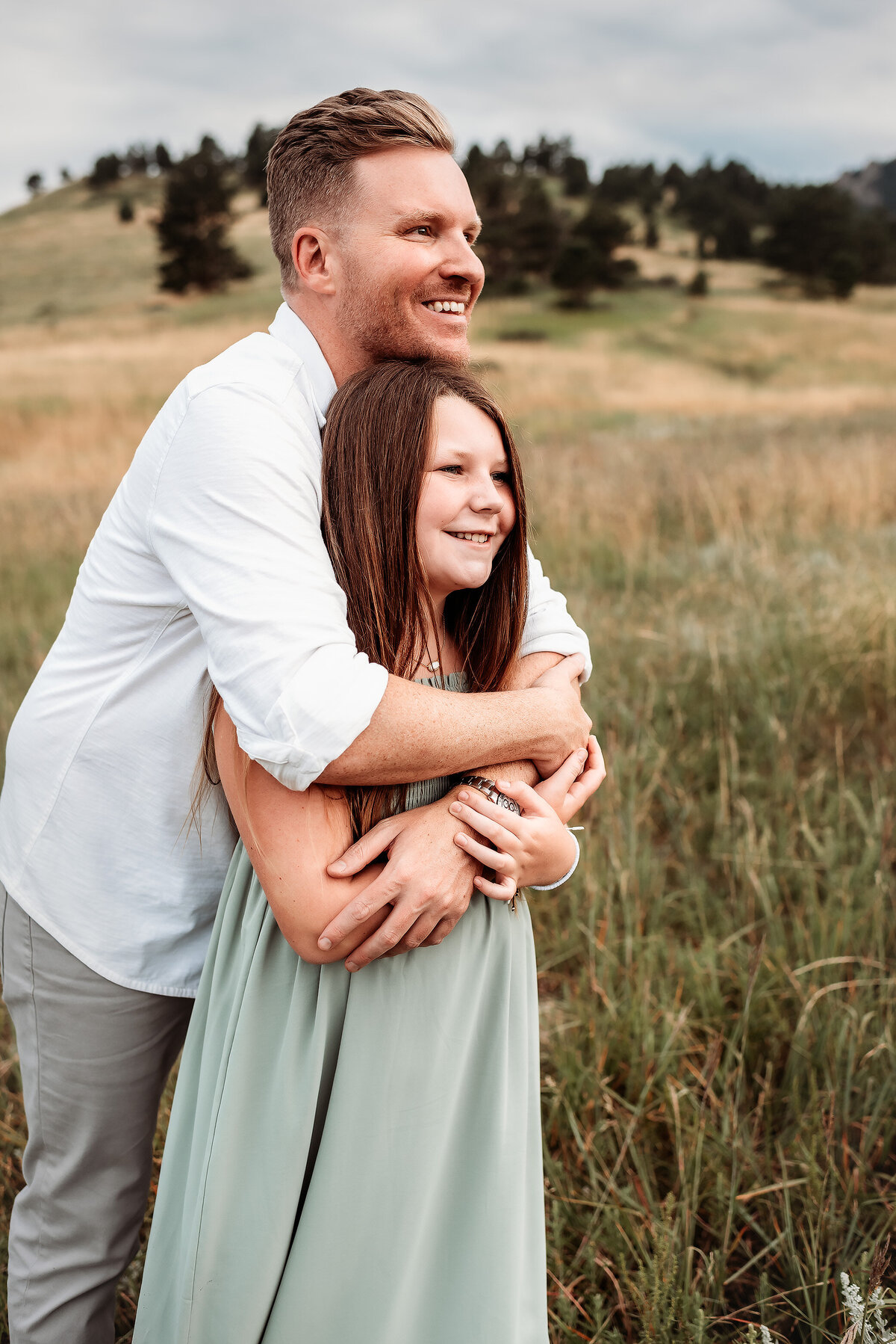 dad hugging his daughter with his arms wrapped around her facing the same direction