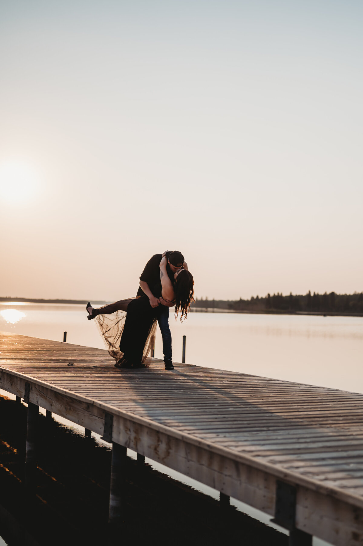 engaged couple kiss on a pier in Edmonton, Alberta