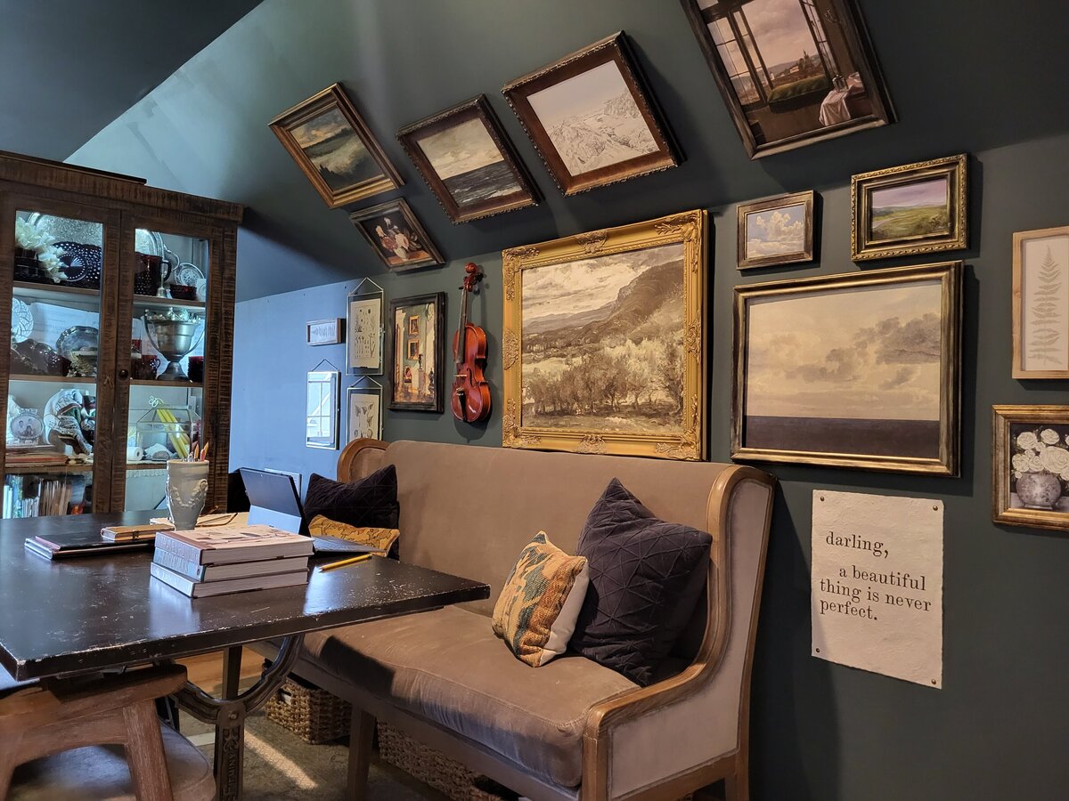 Gallery wall with glass door cabinet and wrought iron table along with grey velvet sofa bench