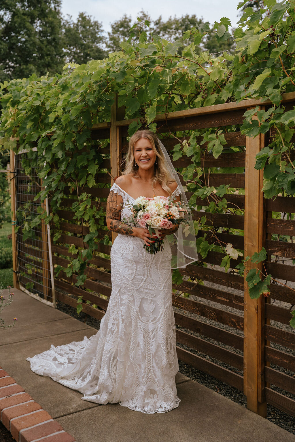 A bride standing outdoors with flowers, representing bridal makeup done by Looks with Libby.